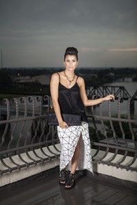 DUCK & DRESSING Both feminine and bold,  this look features a black top with sequined embellishments paired with a graphic, maxi skirt with grid print and a gathered, wrapped front. Finish the look with a black fisherman sandal and a  modern clutch.